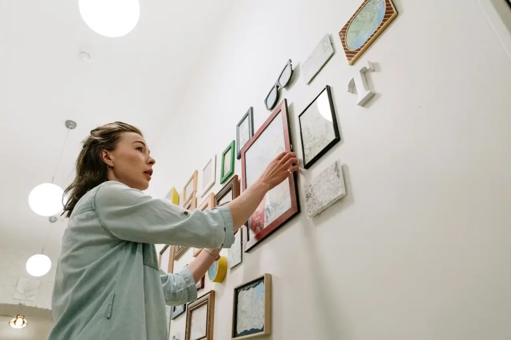 Frau, die Bilder an die Wand hängt und so eine Galeriewand schafft